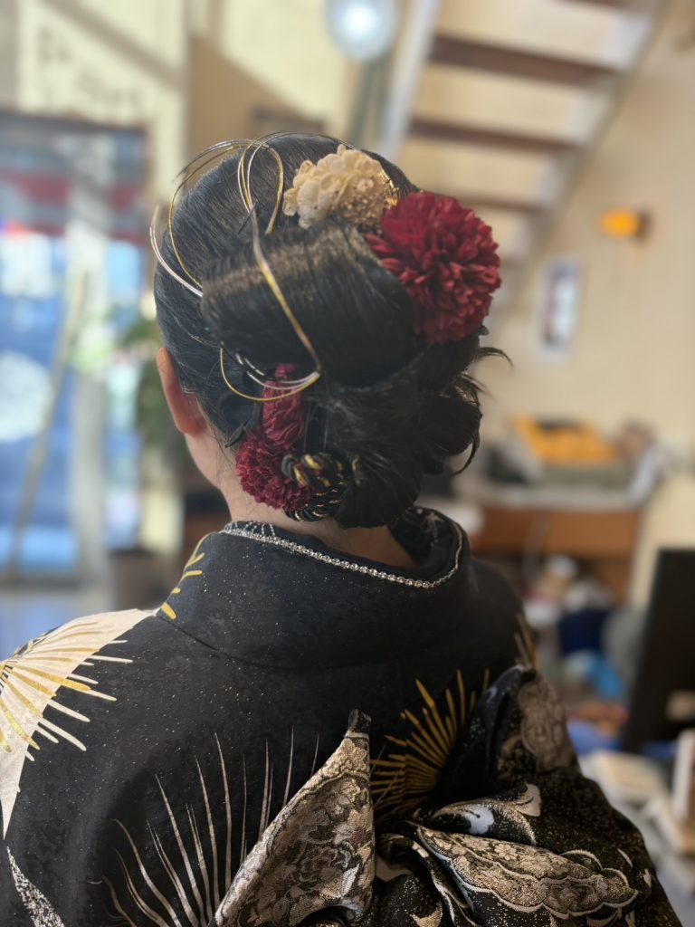 低めシニヨンの成人式アップヘア。水引と花飾りを使い、上品で華やかな後ろ姿の和装ヘアスタイル。