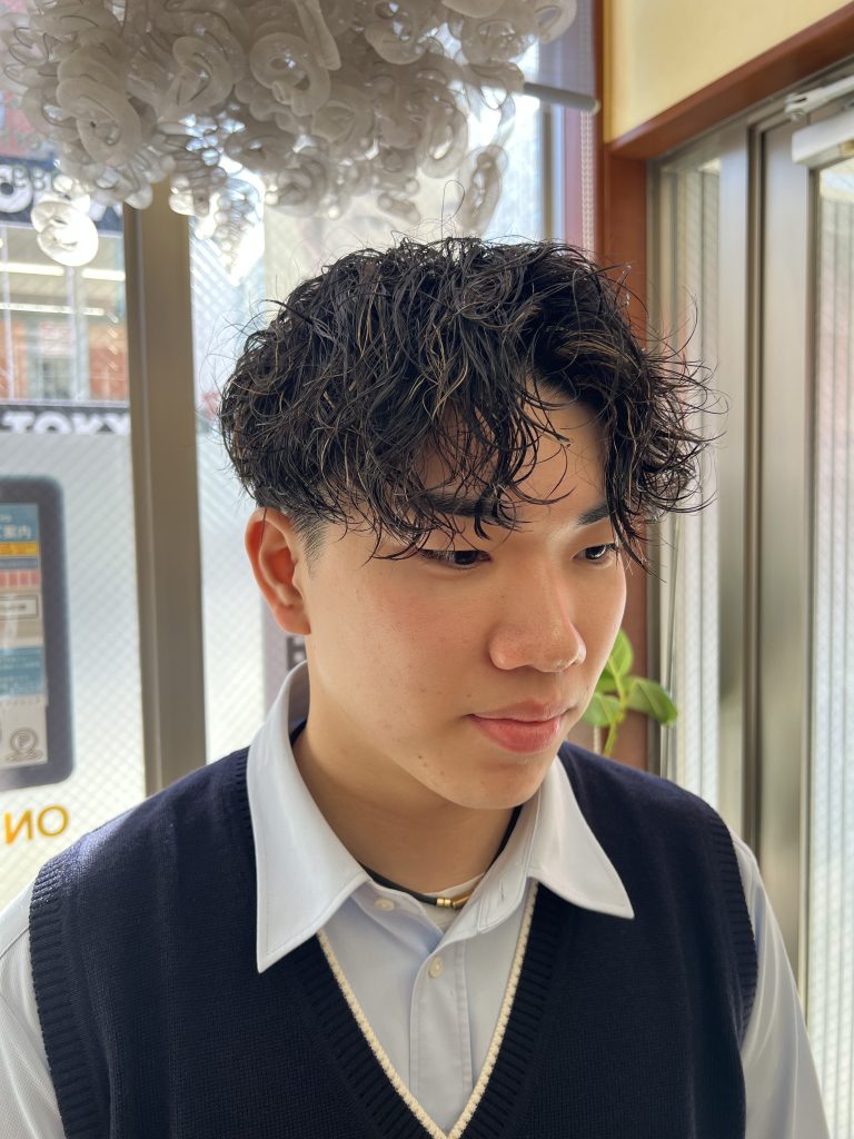 高校卒業後に波打ちスパイラルパーマと細めメッシュを入れたメンズヘアスタイル。黒髪ベースで立体感のあるデザイン。
