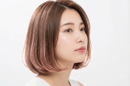 ピンクベージュカラーのナチュラルボブヘアの女性。ツヤ感のある柔らかい質感のスタイル
