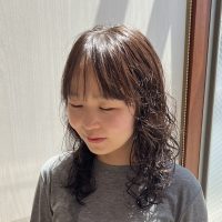 韓国風のゆるいウェーブパーマのミディアムヘア。自然な動きとツヤ感のあるナチュラルな仕上がり。
