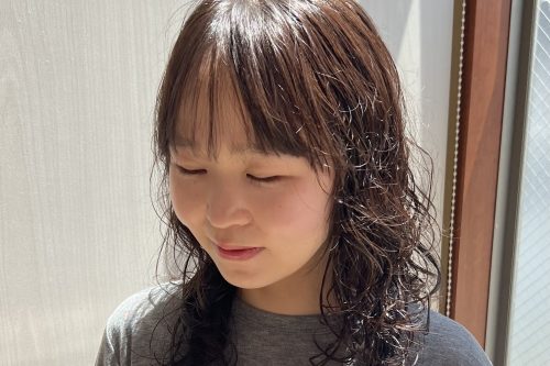 韓国風のゆるいウェーブパーマのミディアムヘア。自然な動きとツヤ感のあるナチュラルな仕上がり。